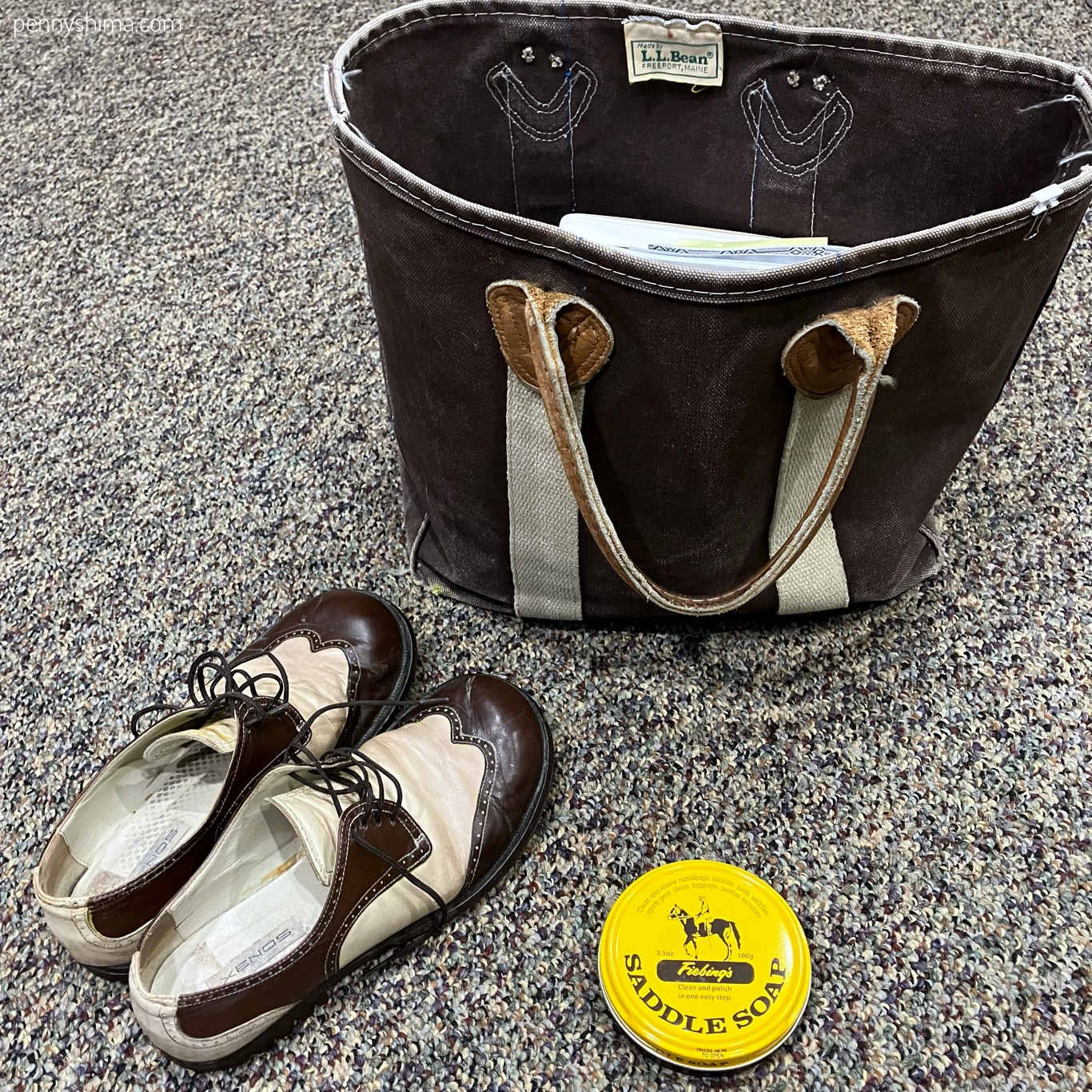brown tote bag with leather handles, a yellow tin of saddle soap, brown and cream oxfords