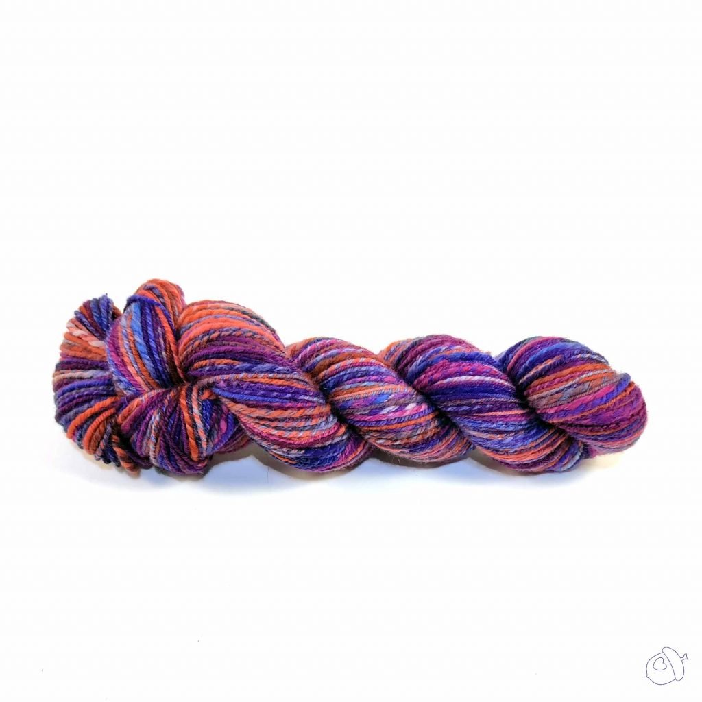 handspun yarn in colors evocative of a summer sunset, reds, oranges, purples, and deep blues