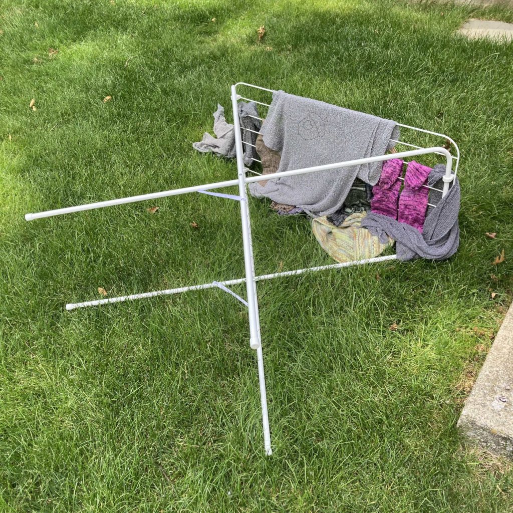 a full drying rack laying on it's side on a grass lawn