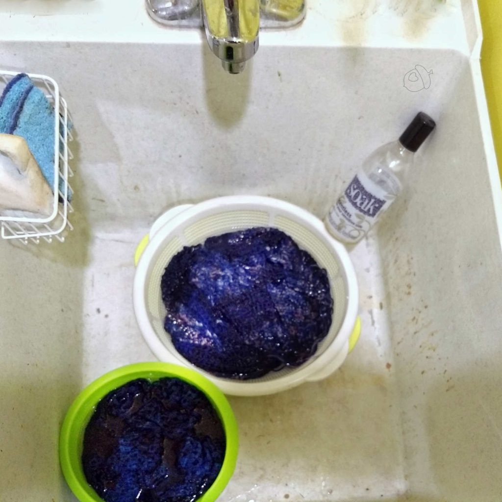 Two round containers in a utility sink with water and wool items soaking.