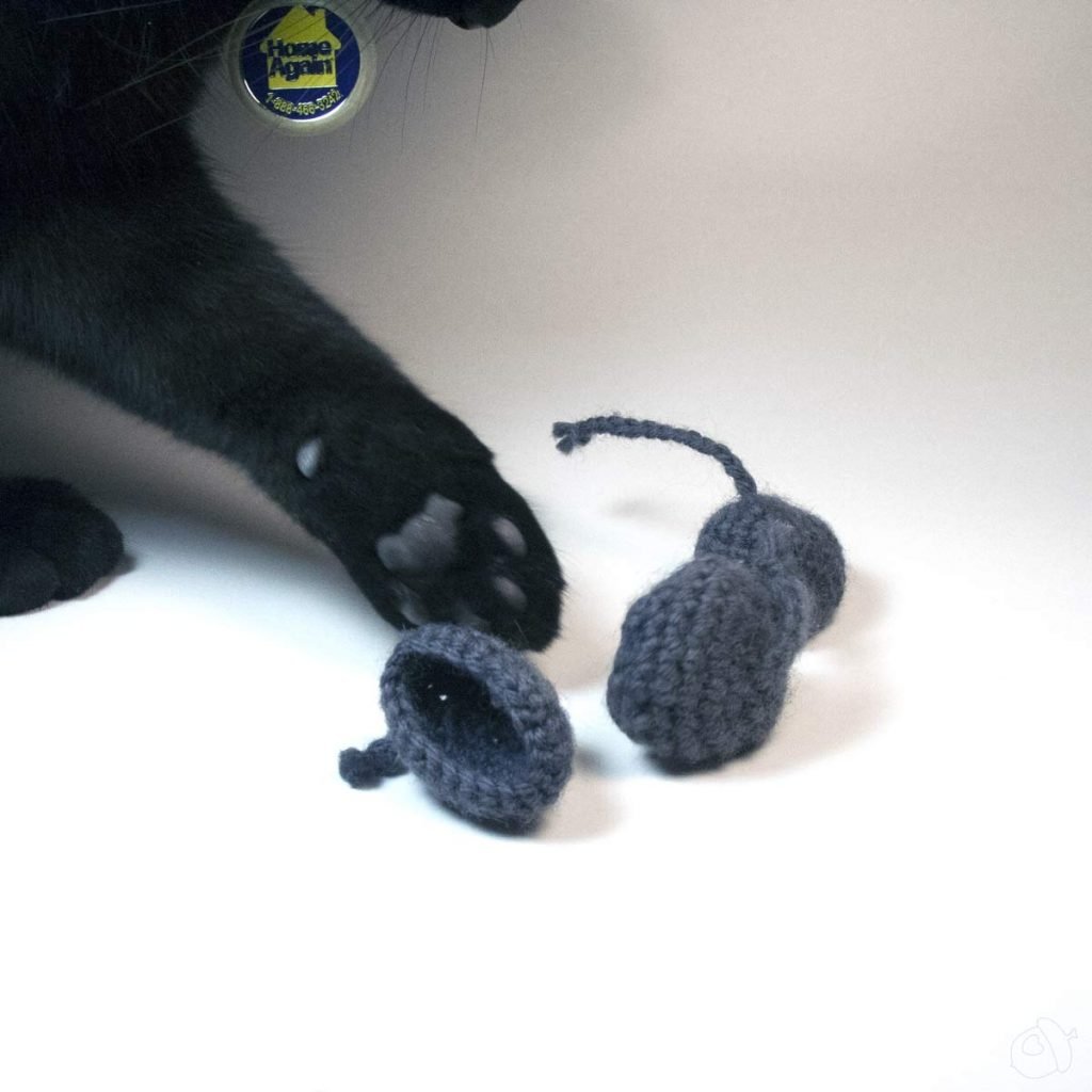 Grey wool cat toy with black cat about to swat one