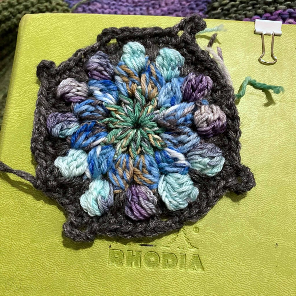 completed crochet motif shown on an anise colored notebook 