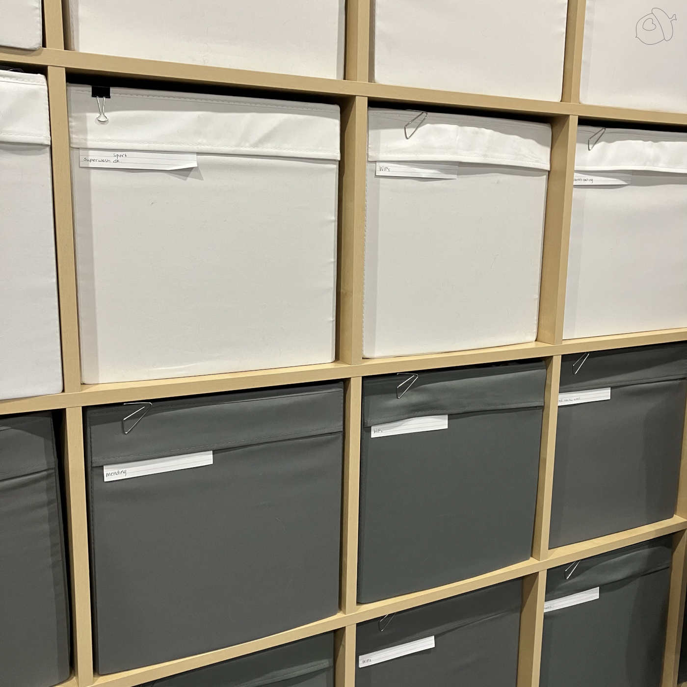 very of ikea expedit unit with white drona boxes and grey ones. all labeled with an index card.