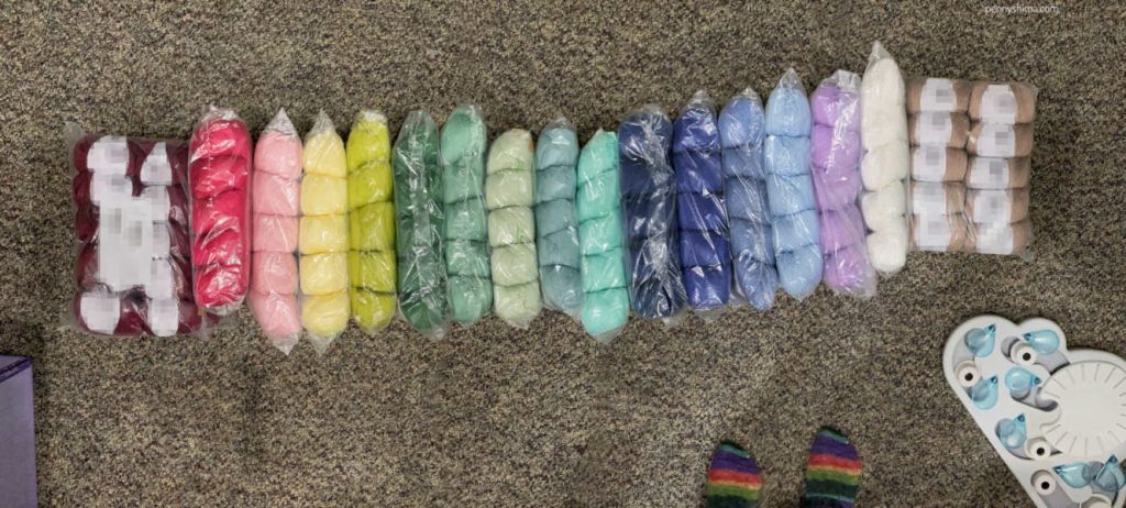 cotton blend yarns arrayed in a rainbow on a multi-brown carpet.