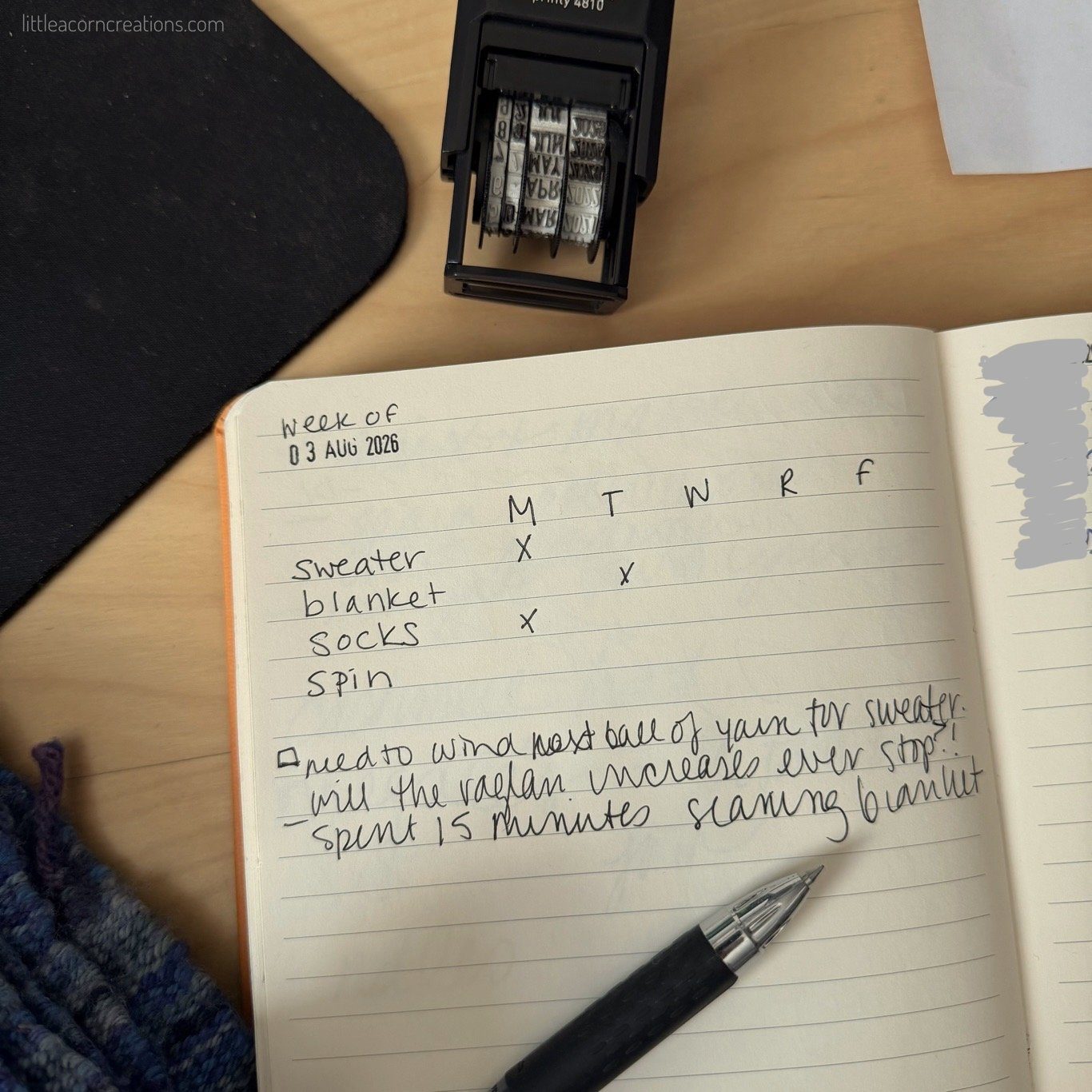 lined notebook, open on a wooden desk. some handwritten text is visible and a pen lays on the notebook.